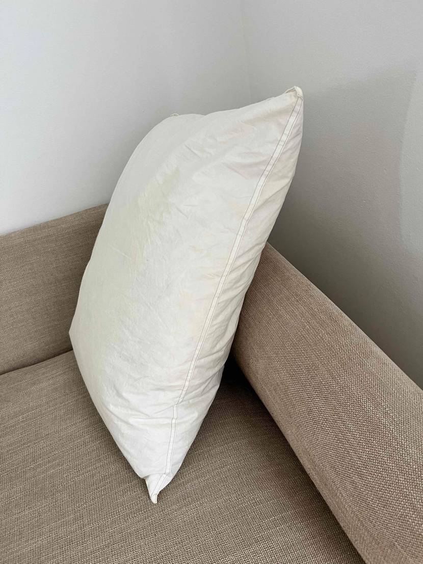 Ikea Kopfkissen getestet: ein weißes Kissen auf einer hellen Couch, von der Seite betrachtet.
