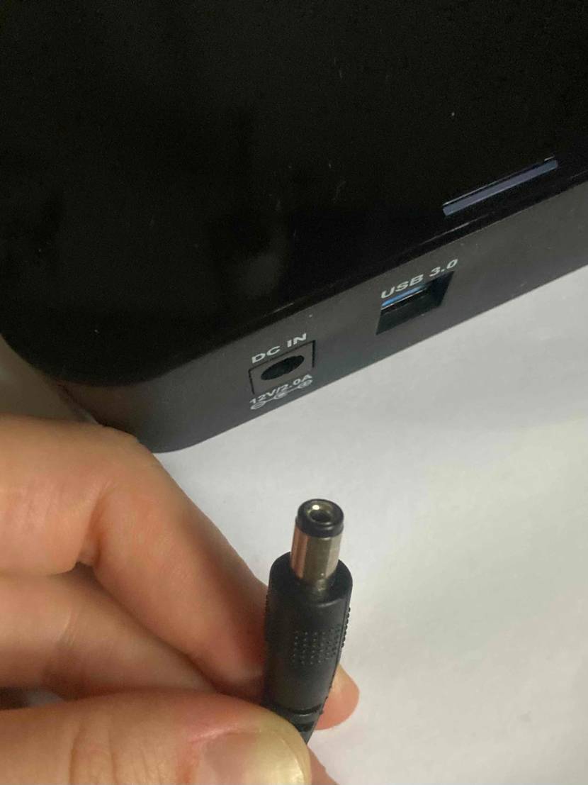 Detailansicht einer schwarzen, getesteten 8-TB-Festplatte mit Fokus auf den Anschluss für DC IN sowie USB 3.0 und Hand, die davor einen Audiokabel-Stecker hält.