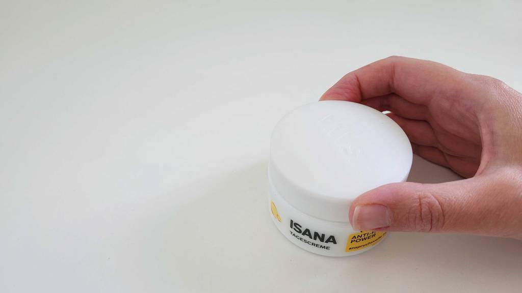 Hand schraubt Deckel einer Isana Tagescreme-Dose auf