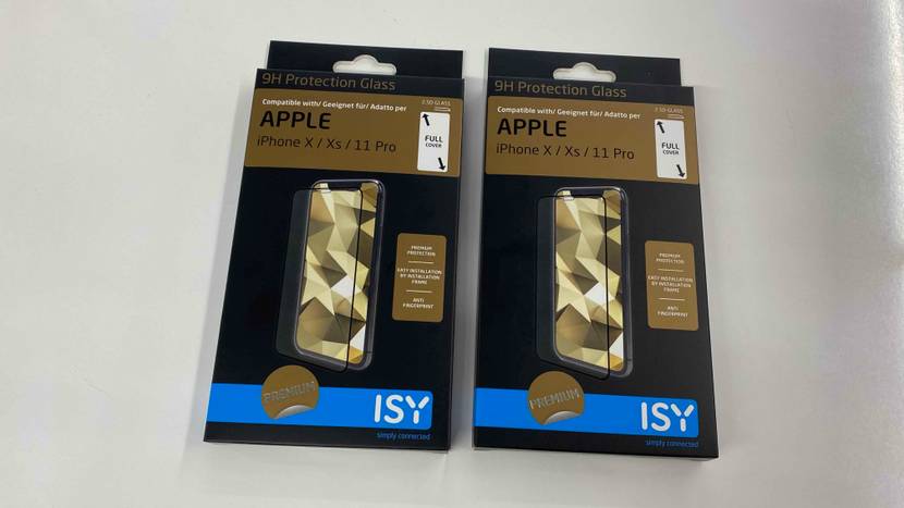 Zwei Verpackungen von getesteten iPhone-X-Panzerfolien befinden sich nebeneinander auf einer hellgrauen Oberfläche.