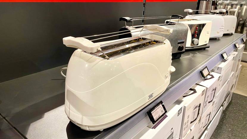 Langschlitztoaster getestet: Ein Gerät von schräg seitlich in einer Ausstellung neben anderen Geräten inklusive Preisschildern.