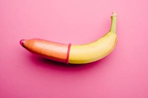 banane ueber die ein kondom gezogen wurde vor pinkem hintergrund