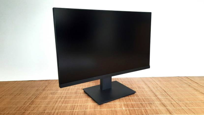 Vorderansicht auf einen schwarzen, getesteten 24-Zoll-Monitor mit Flachbildschirm, der sich mit seinem Standfuß auf einer hellbraunen Bastmatte befindet.