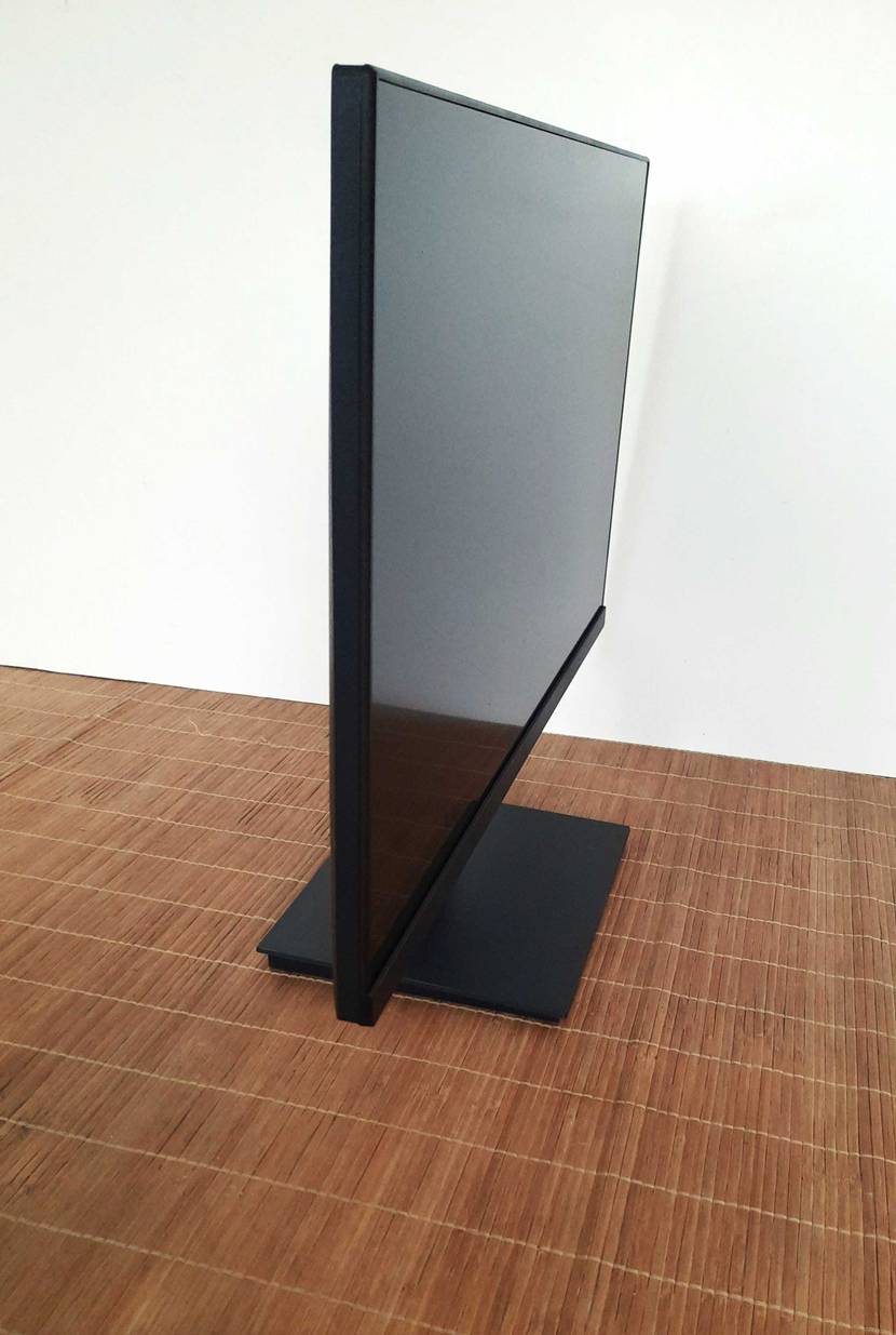 Seitenansicht eines Koorui 24-Zoll-Monitors im Test, der inklusive Standfuß vor einer weißen Wand auf einer hellbraunen Bastmatte steht.