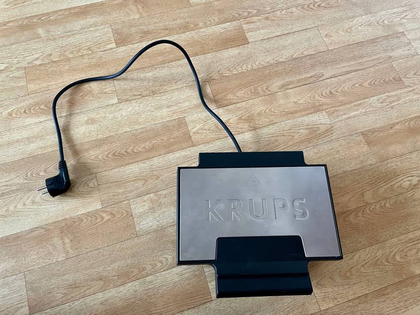 Geschlossenes Waffeleisen von Krupps steht auf dem Boden mit Stromkabel daneben liegend.