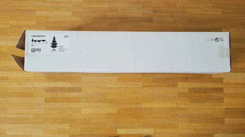 Künstlicher-Weihnachtsbaum im Test: Weihnachtsaum in Verpackung auf Holzboden