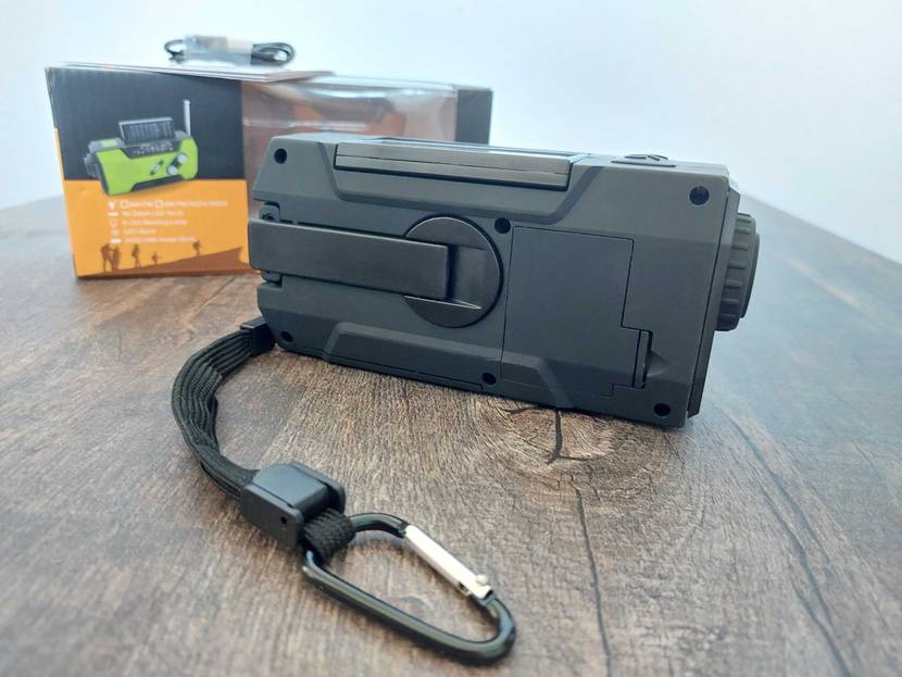Kurbelradio im Test mit Anhänger liegt auf einem Holztisch neben der Verpackung. 