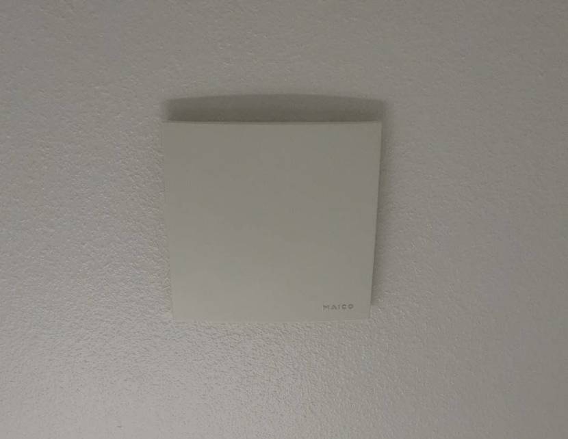 Weißer, quadratischer Maico Badlüfter im Test ist auf einer weißen Wand montiert.