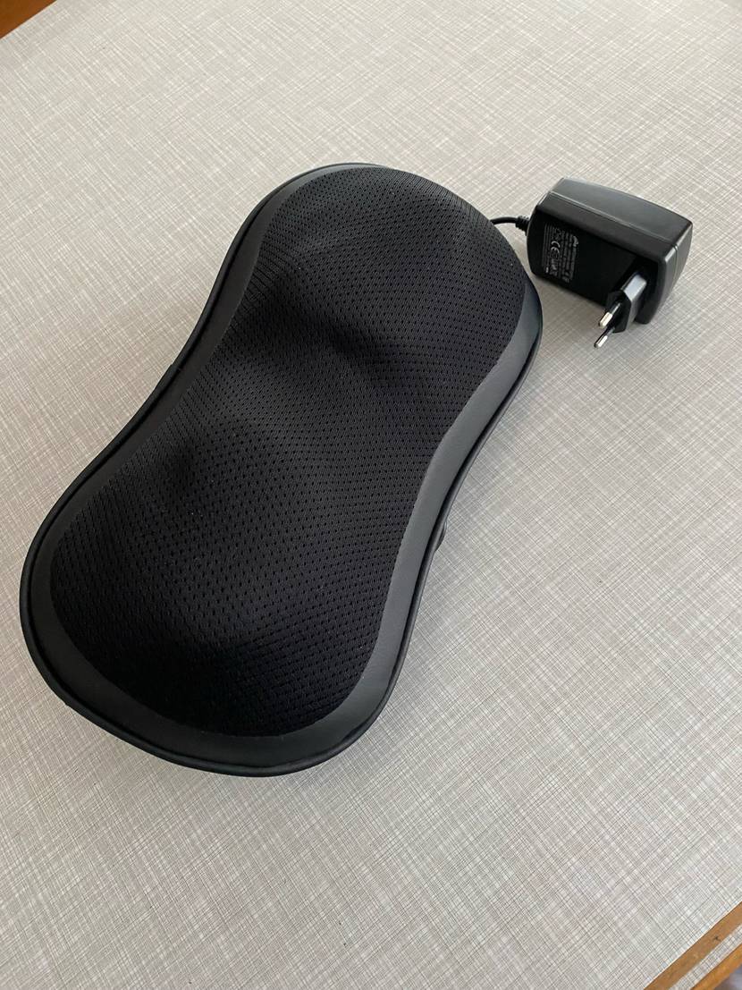 Im Test: Ein Massagegerät und sein Stromstecker auf einer grauen Fläche von schräg oben.