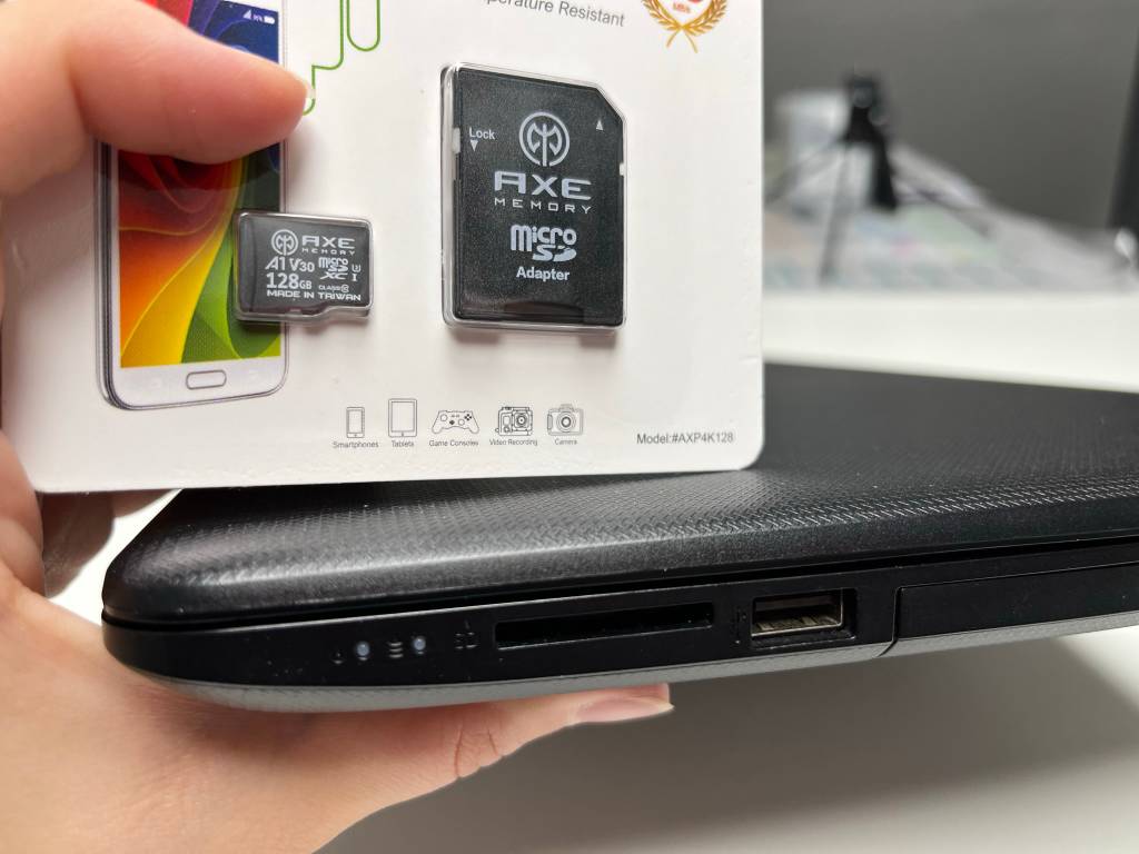 Hand hält Laptop und Micro-SD-Karte in Verpackung.