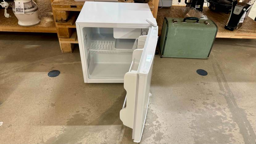 Mini-Kühlschrank getestet: Ein geöffneter Mini-Kühlschrank vor Holzpaletten auf einem Betonboden.