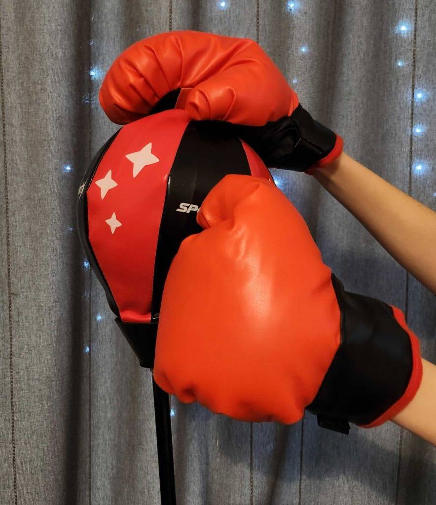 Zwei Kinderfäuste in Boxhandschuhen schlagen auf einen getesteten Kinder-Boxsack.
