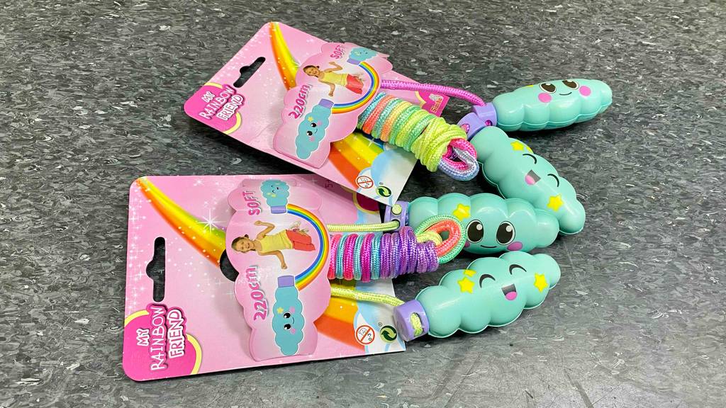 Zwei bunte getestete Springseile My Rainbow Friend mit türkisfarbigen Soft-Griffen liegen auf einem grauen Boden.