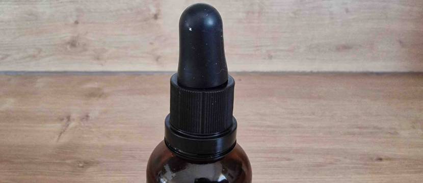 Vitamin-D-Präparat im Test: Geschlossene blickdichte Braunglas-Flasche mit schwarzem Pipetten-Verschluss vor Holzhintergrund.