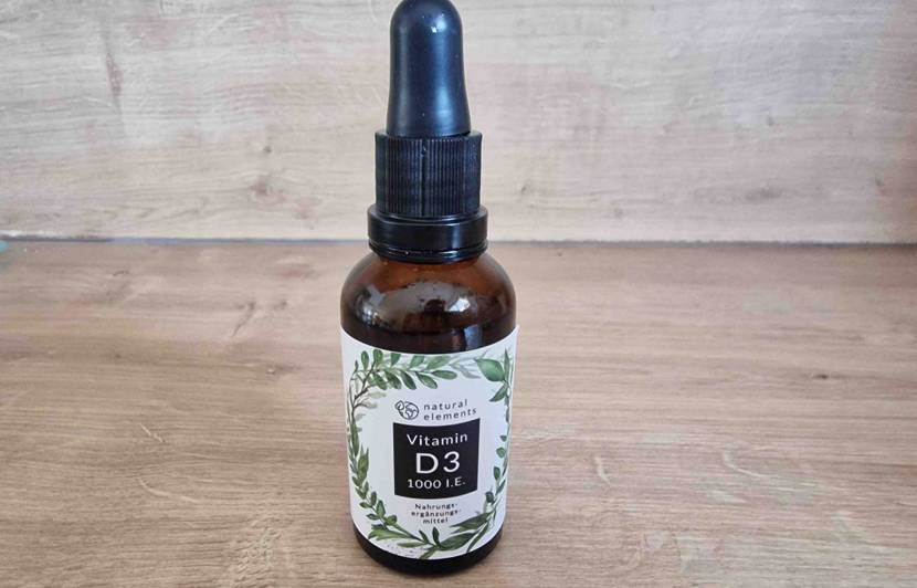 Natural Elements Vitamin-D-Präparat im Test: Geschlossene blickdichte Braunglas-Flasche mit Pipetten-Verschluss steht auf Holz.