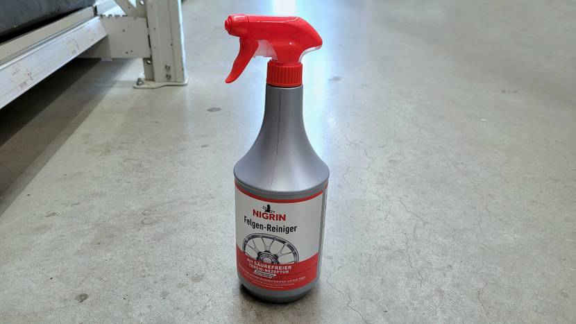 Eine Flasche Felgenreiniger steht zum Testen auf einem hellen Boden.