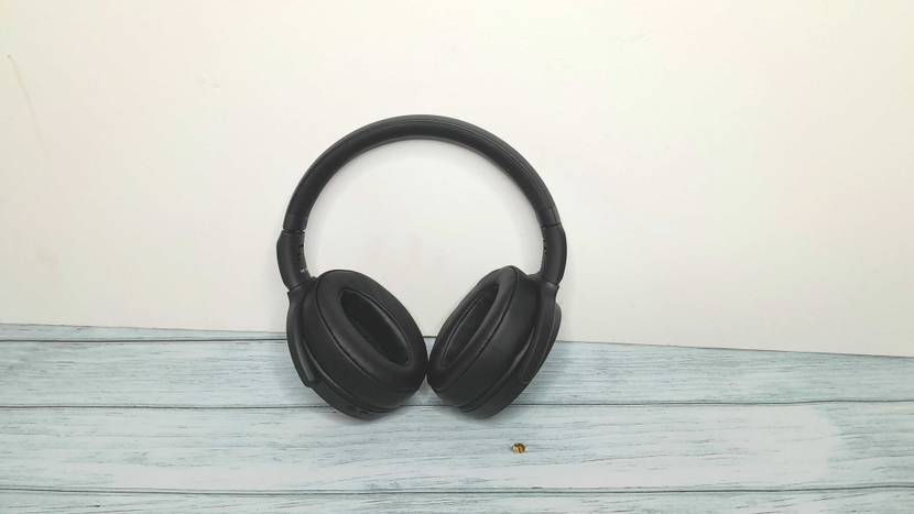Ein getesteter Noise-Cancelling-Kopfhörer von vorne auf einer grauen Oberfläche vor einer weißen Wand.