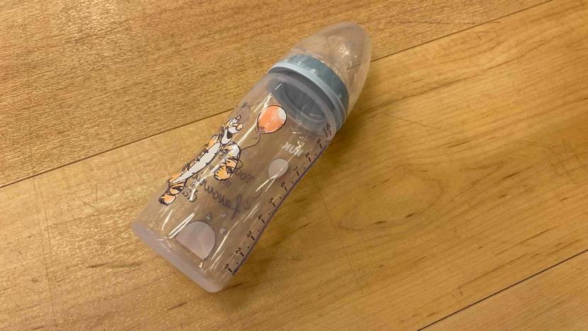 Babyflasche mit Disneymuster liegt auf einem Holzboden