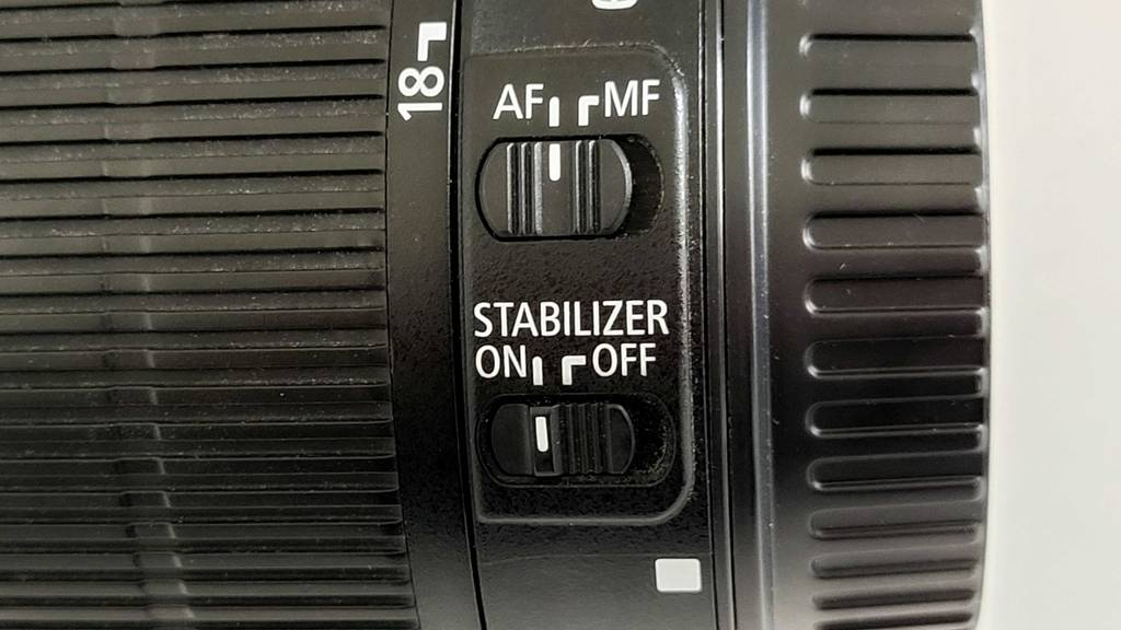 Schwarzes Kameraobjektiv der Marke Canon mit einem Stabilisator.
