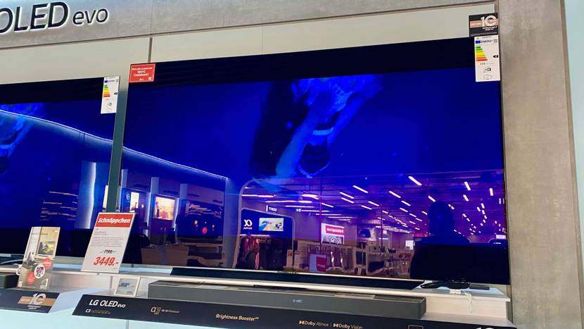 OLED TV getestet: Ein Gerät von schräg unten vor einer hellen Fläche neben anderen Produkten.