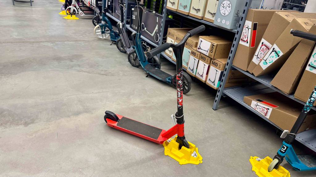 Ein roter Stunt-Scooter steht zum Testen in einem langen Hallengang.