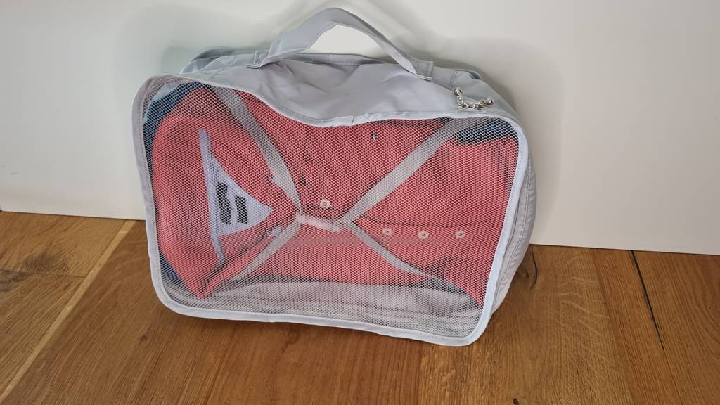 Ein Betllemory Packwürfel befüllt mit einem T-Shirt vor einer weißen Wand.