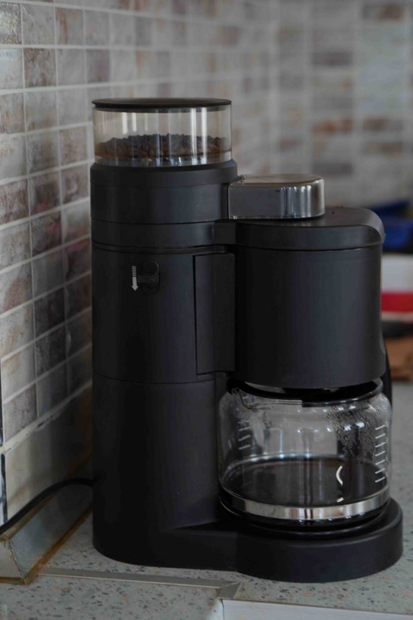 Kaffeemaschine mit Mahlwerk im Test: Das schwarze Modell steht inklusive Glaskanne und Bohnenbehälter auf einer grauen Arbeitsfläche.
