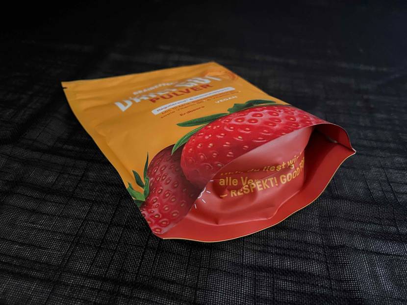 Darmbakterien-Pulver getestet: Boden einer Packung in Nahaufnahme auf einer dunklen Stofffläche.