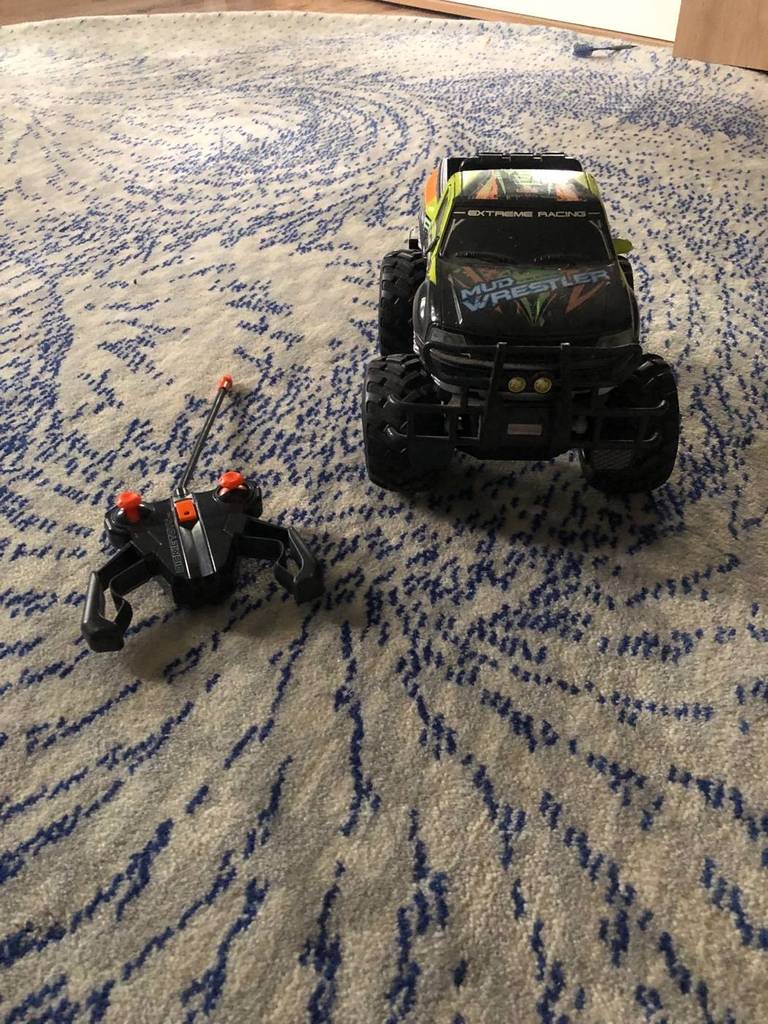 Im Test: Ferngesteuertes Auto RC Ford in schwarzem Design mit grellen Applikationen befindet sich neben der Fernsteuerung auf einem Teppich.