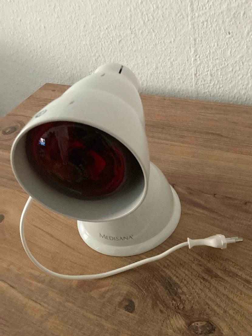 Rotlichtlampe getestet: Ein Gerät von schräg vorne mit Stromkabel auf einem Holztisch.
