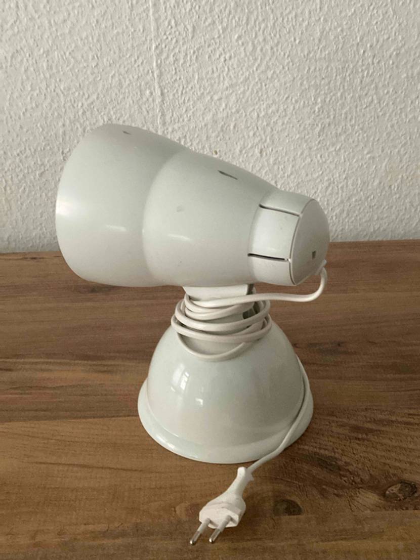 Eine getestetete Rotlichtlampe von der Seite vor einer hellen Wand.