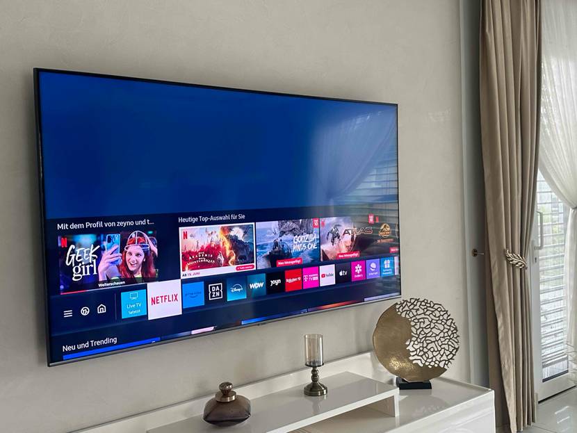 80-Zoll-Fernseher-Test: Ein eingeschalteter Fernseher ist an einer weißen Wand montiert.