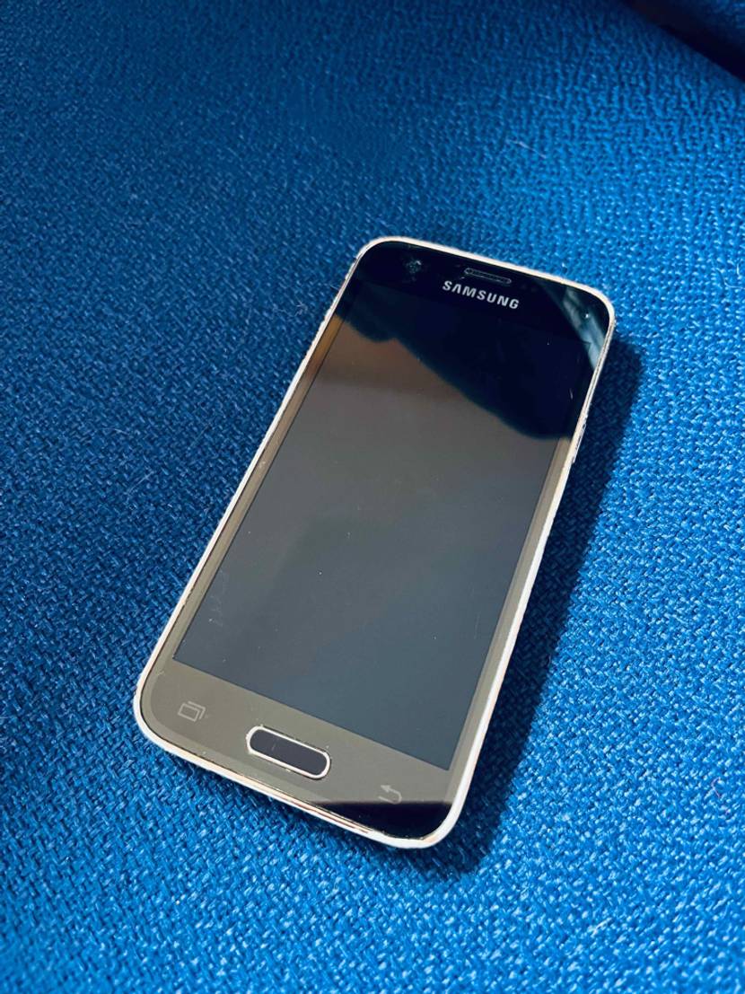 Kleine Smartphones getestet: Ein Modell von Samsung liegt mit dem schwarzen Display nach oben auf einem blauen Untergrund.