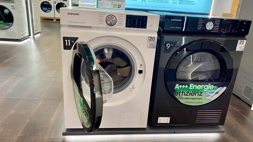 Samsung Waschmaschine getestet: Ein Gerät mit geöffneter Klappe neben anderen Produkten in einer Austellung.
