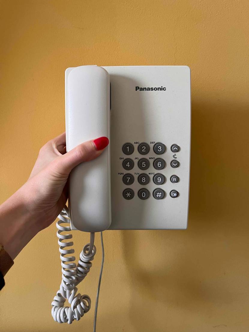 Schnurtelefone-Test: Schnurtelefon wird vor gelbe Wand gehalten.