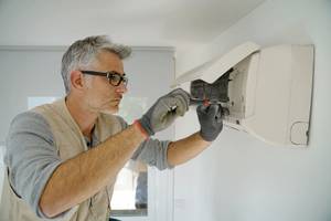 handwerker mit handschuhen der eine split klimaanlage installiert
