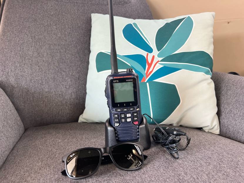 Funkgeräte-Test: GPS-Funkgerät inklusive Basisstation befindet sich auf einem grauen Sessel mit grün-buntem Kissen und Sonnenbrille.
