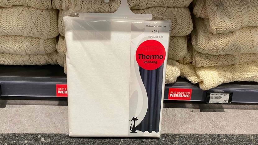 Im Test: Ein verpackter Thermovorhang von vorne vor einem Regal mit gestrickten Decken.