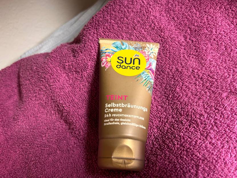 Gesichtsbräuner im Test: eine Tube von Sun dance liegt auf einen lila Handtuch.