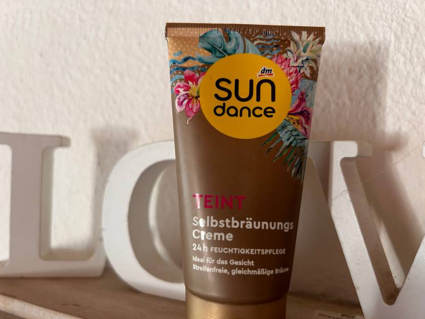 Eine Tube Sun dance Gesichtsbräuner steht zum testen in einem Regal vor großen Buchstaben.