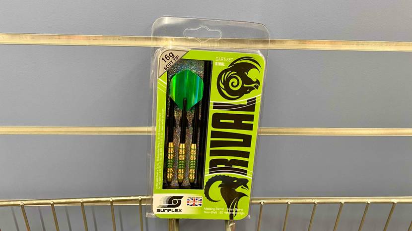 In einem Verkaufsbereich vor grauer Wand stehen Sunflex Rival Dartpfeile im Test in ihrer hellgrünen Verpackung ausgestellt.