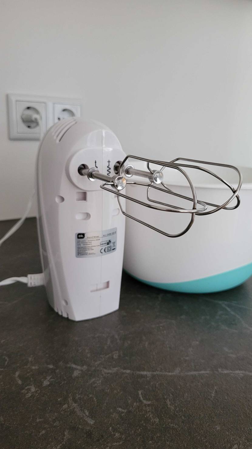 Handmixer wird aufgeladen in der Küche neben Plastikschüssel