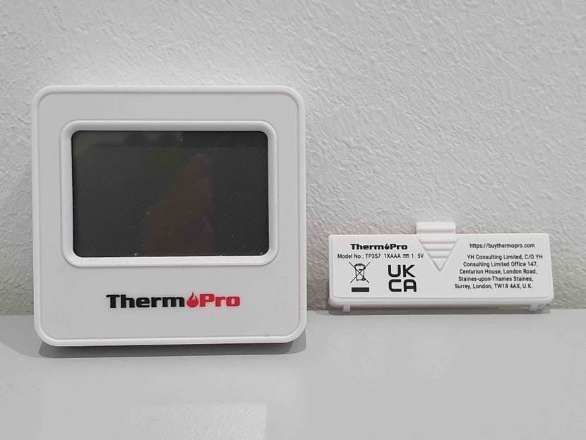Frontansicht eines getesteten Smart-Home-Thermostats, die Abdeckung des Batteriefachs liegt daneben.