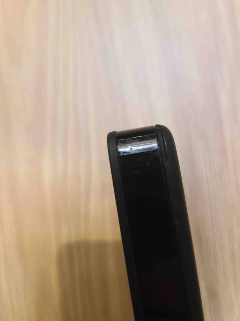 Ansicht der abgerundeten Ecke vor einer Holzoberfläche, eines schwarzen, mobilen WLAN-Routers im Test.