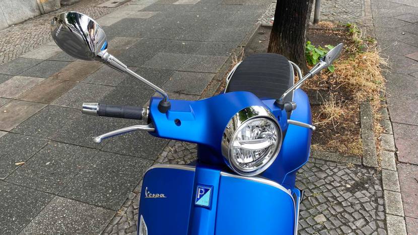Vorderansicht eines auf der Straße parkenden blauen Vespa Motorrollers im Test.