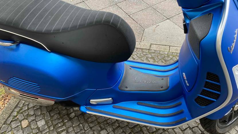 Ansicht von oben auf Sitz und Trittfläche eines getesteten blauen Vespa Motorrollers.