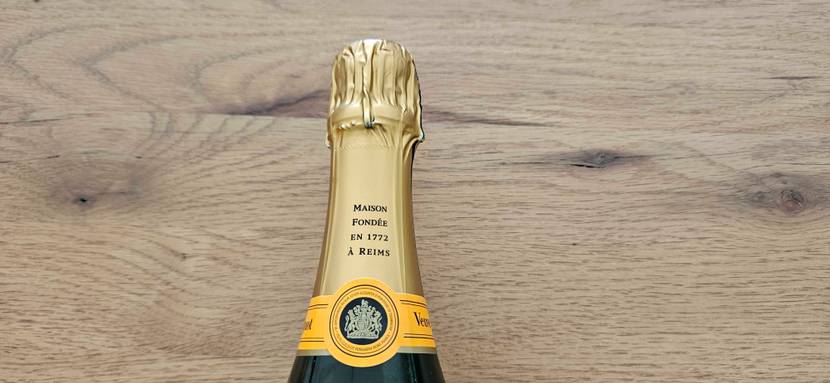 Im Test: Nahaufnahme des Flaschenverschlusses eines Champagners vor einer Holzfläche.