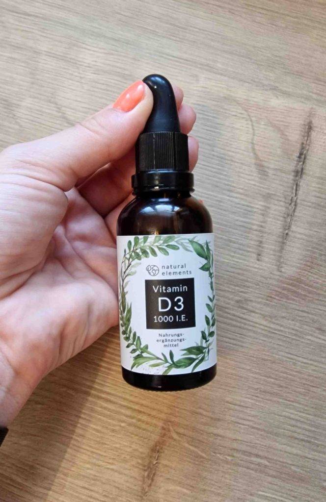 Hand hält getestetes Vitamin-D3 in Tropfenform.