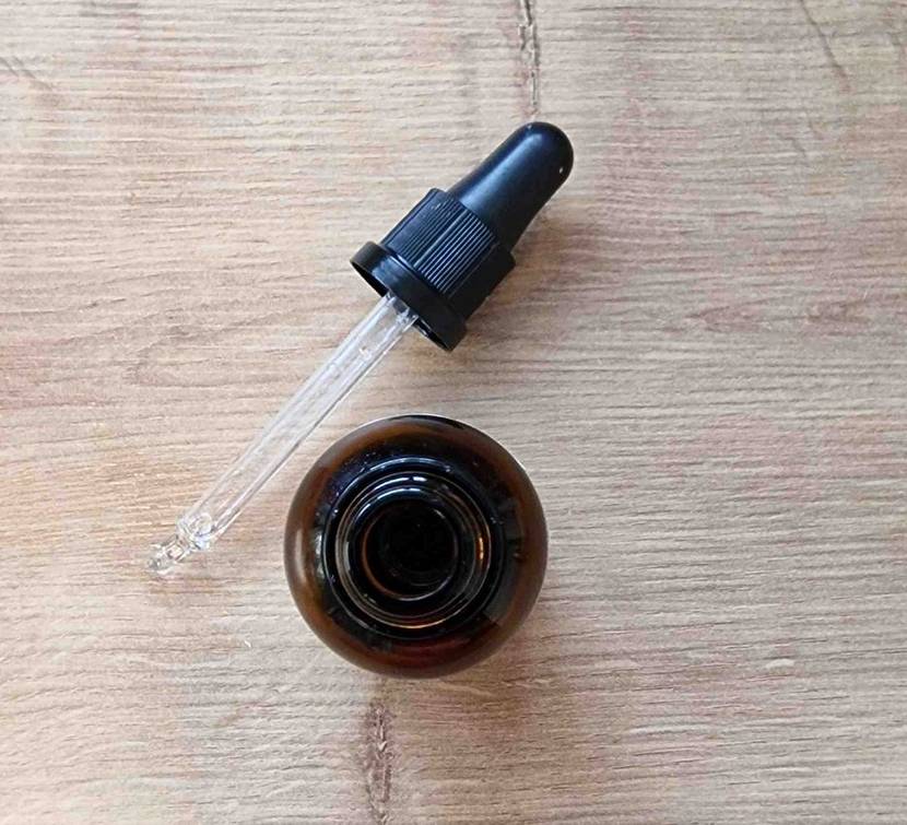Vitamin-D3 im Test: Flasche von Vitamin-D3-Tropfen liegt geöffnet auf Holzboden. Pipette liegt neben Flasche.