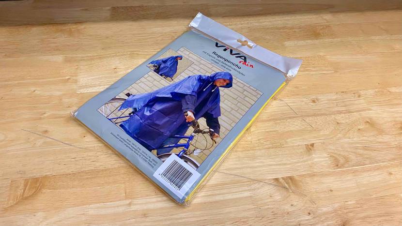 Regenponcho getestet: Ein originalverpacktes Produkt mit Foto auf der Vorderseite auf einem Holzboden.